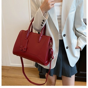 Detail view of red lychee grain leather handbag with gold hardware and H charm