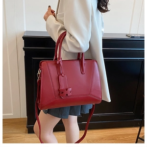 Close-up of elegant red tote bag with H-pendant decoration and dual top handles