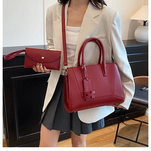Detail of deep red leather tote and matching clutch bag shown on a professional model