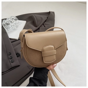 Close-up of khaki saddle bag featuring smooth leather and suede patchwork with buckle