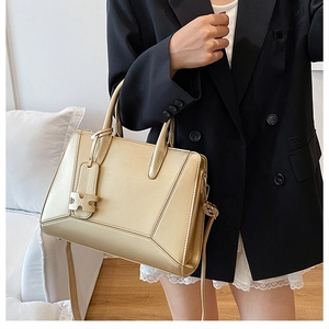 Detail view of champagne gold crossbody bag with geometric stitching and H-shape buckle