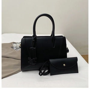 Detail of black matte tote bag set featuring a curved handle and matching envelope clutch