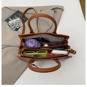 Interior view of large capacity brown leather tote showing organized compartments and items
