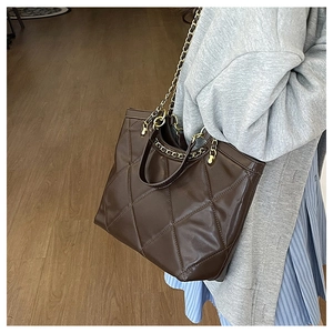Detail of dark brown quilted tote bag with gold chain strap and PU leather texture