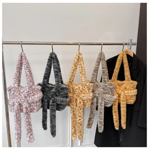 Detail of five faux fur tote bags with long ribbons on a metal rack display