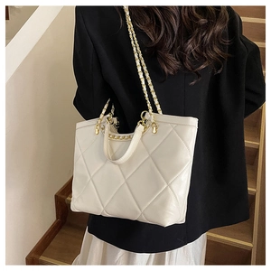 Close-up of quilted white tote bag with gold chain strap and textured diamond pattern