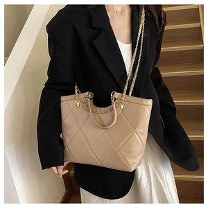 Detail of khaki quilted shoulder bag with gold chain strap and ring handle worn with outfit