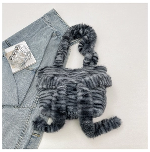 Macro detail of fluffy grey zebra striped plush handbag with dangling fuzzy pom decorations