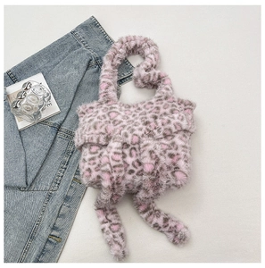 Close-up of pink leopard faux fur handbag featuring a large decorative bow on white background