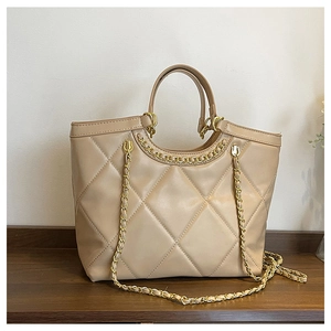 Detailed view of beige quilted tote bag with gold metal chain straps and smooth texture