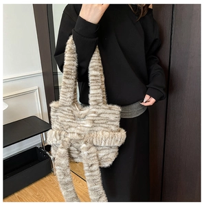 Close-up of plush tote bag with bow detail on female model in stylish interior