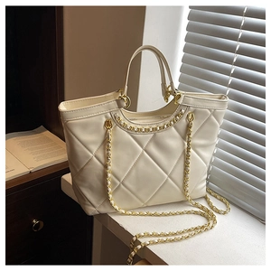Macro detail of cream quilted tote bag with golden chain strap and leather texture