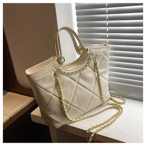 Detailed view of cream quilted tote bag featuring gold chain strap and large diamond stitching