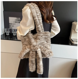 Detail of striped faux fur shoulder bag with large bow decoration worn by model