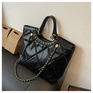 Close-up of black quilted tote bag with gold chain strap and detailed stitching