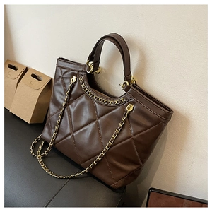 Detail of dark brown quilted tote bag showing rhombus stitching and gold chain strap