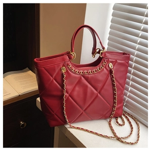 Detail of red quilted faux leather tote bag with elegant golden chain handle and strap
