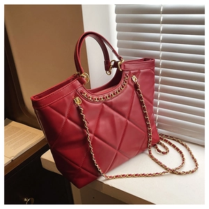 Detail of red quilted leather tote bag with gold chain strap and stitching texture