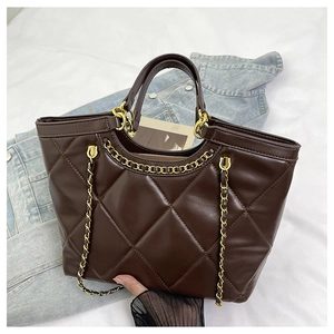 Detail of dark brown quilted tote bag with gold chain strap and luxury leather texture
