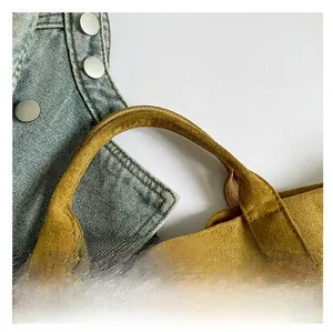 Macro view of sturdy suede tote bag handle with thick stitching on mustard yellow leather