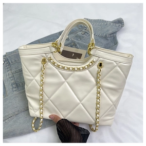 Close-up of quilted white tote bag featuring gold chain straps and rhombic pattern