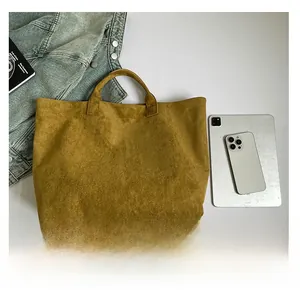 Detailed macro view of mustard yellow suede tote bag with white TOTE BAG text print