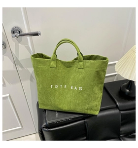 Macro detail of the green suede tote bag with white text against home interior decor