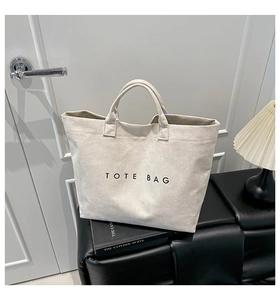 Minimalist cream white suede tote bag featuring a bold black TOTE BAG print on the front