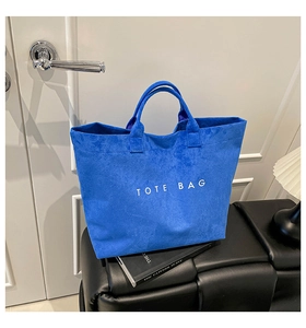 Detailed view of the blue suede tote bag texture with white TOTE BAG lettering
