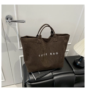 Detailed close-up of dark brown suede tote bag featuring white TOTE BAG text print
