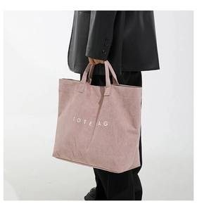 Close-up of pink corduroy tote bag featuring white TOTE BAG text and soft ribbed texture
