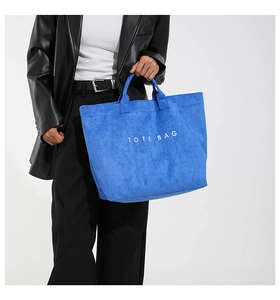 Close-up of royal blue suede tote bag with white text detail and premium texture
