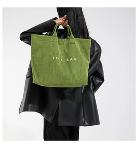 Detail of olive green suede tote bag with white TOTE BAG lettering and sturdy handles