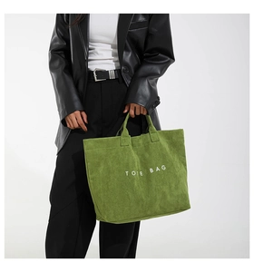 Close-up of grass green suede tote bag showing minimalist design and white lettering