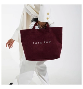 Deep red suede tote bag shown on a model for a stylish large-capacity commuter look
