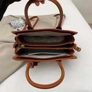 Brown faux leather tote bag with dual ring handles and spacious triple interior compartments