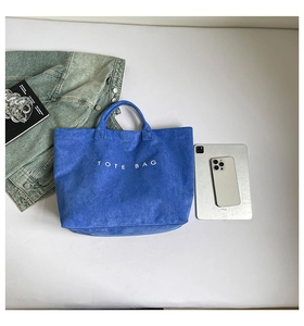 Klein blue faux suede tote bag with white TOTE BAG text print shown beside accessories