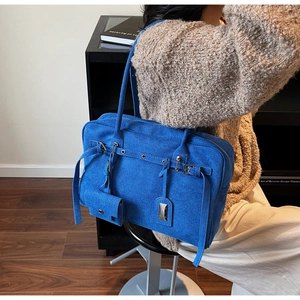 Detail of royal blue suede tote bag with metal buckle and matching small hanging pouch