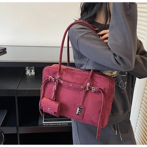 Detail of burgundy suede tote bag featuring silver hardware and a small coin purse pendant