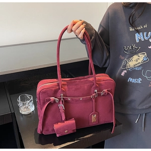 Close-up of burgundy suede tote bag featuring a decorative buckle and mini coin purse