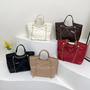 Quilted tote bags with gold chains in five colors displayed on white geometric stands
