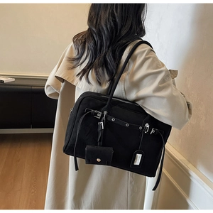 Detail of a black large-capacity tote bag with silver buckles on a beige trench coat