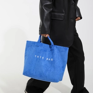 Royal blue suede tote bag with white TOTE BAG text print shown in a stylish side view