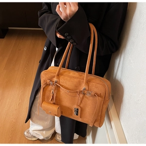 Detail of suede tote bag in orange-brown with matching mini pouch and metal accents