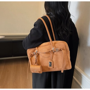 Brown suede tote bag shown on shoulder featuring decorative buckle and mini pouch detail