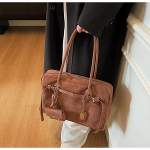 Detailed view of brown suede tote bag with decorative buckle straps and hanging pouch