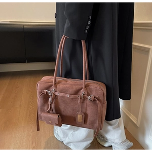 Detail view of large dark brown suede tote bag with decorative mini pouch and metal eyelets