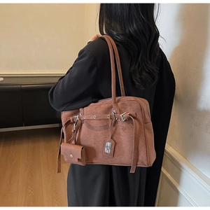 Detailed close-up of brown suede tote bag featuring a decorative mini pouch and silver buckles