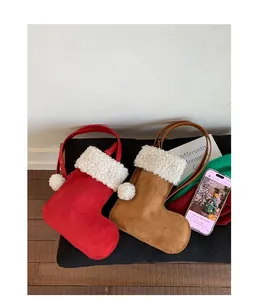 Macro shot of festive suede Christmas stocking bags with plush fur trim and pom-poms