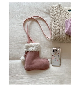 Close-up of pink faux suede boot-shaped bag with white fleece trim and pompom detail